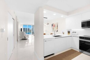 A modern kitchen with white cabinetry, a built-in oven, and a microwave. - Le Marina Bay PH4 STR-03600 (Sunny Isles Beach)