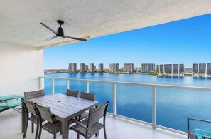 A balcony with a table and chairs, overlooking a body of water and a cityscape. - Le Marina Bay PH4 STR-03600 (Sunny Isles Beach)
