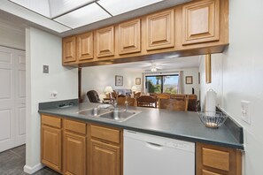 A kitchen with wooden cabinets, a double sink, and a dishwasher.