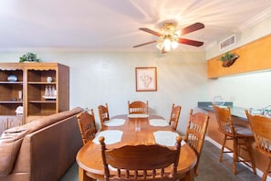 A dining area with a wooden table and chairs, a ceiling fan, and a kitchen counter. - Panoramic Ocean Views at Ponce Landing 2 (St. Augustine)