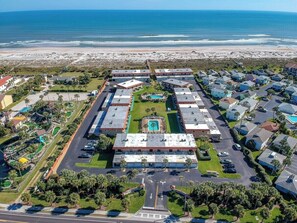 An aerial view of a coastal hotel with multiple buildings, a central pool, and a beach in the background. - Panoramic Ocean Views at Ponce Landing 2 (St. Augustine)