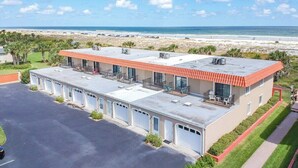 Een hotel met parkeerplaats, uitzicht op het strand en een gebouw met een rood dak.