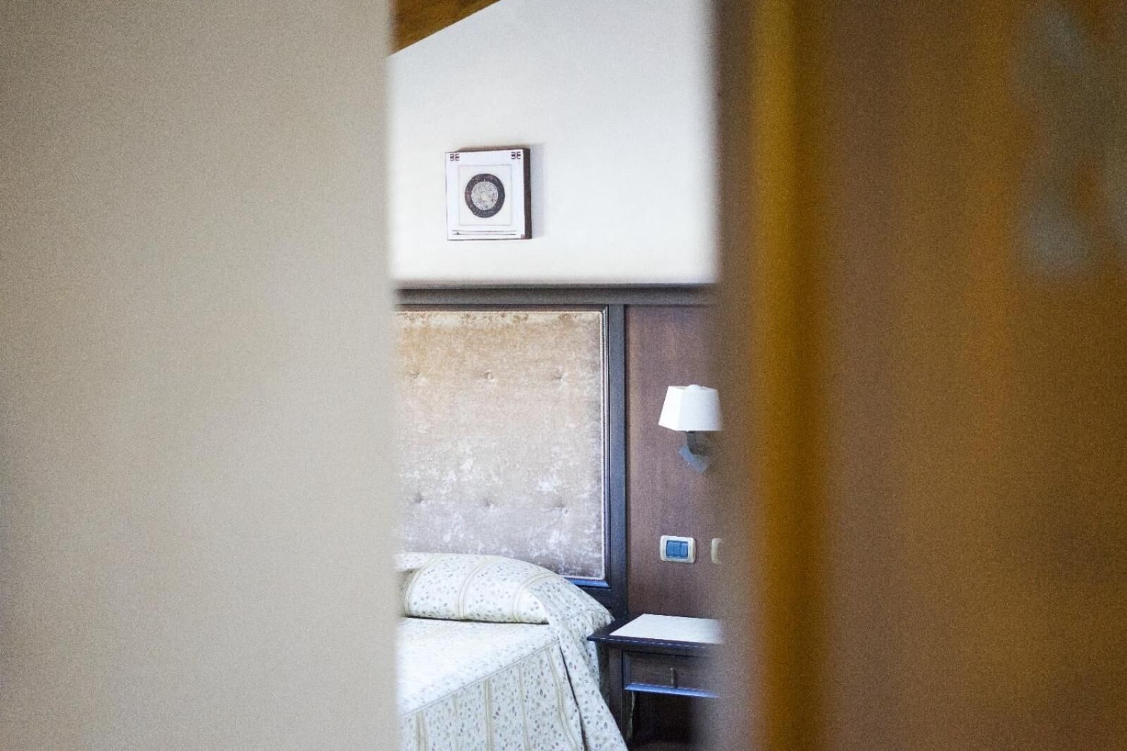 Ein Schlafzimmer mit einem Bett, einem Nachttisch, einer Wandlampe und einem gerahmten Bild.