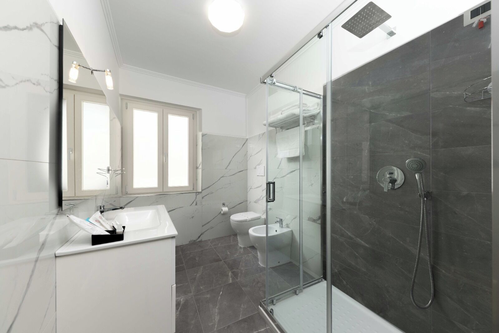 Une salle de bain moderne avec une douche à parois de verre, un lavabo blanc et des toilettes.