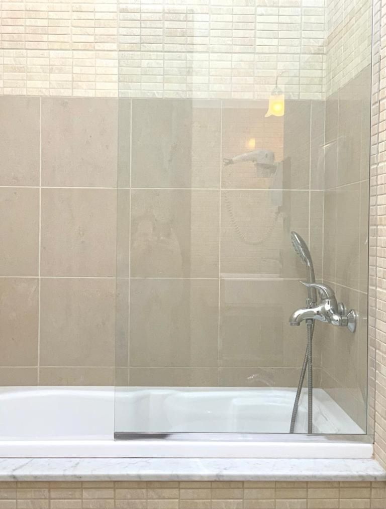 A glass-enclosed shower area with a built-in bathtub.