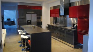 Una cocina moderna con electrodomésticos de acero inoxidable, una isla central con taburetes y armarios color rojo.