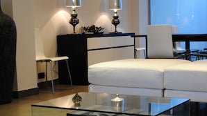 Una sala moderna con una mesa de centro de vidrio, sofá blanco y dos lámparas.
