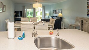 Una cocina compacta con lavabo, una zona de comedor con mesa y sillas, un sofá y vistas al exterior.