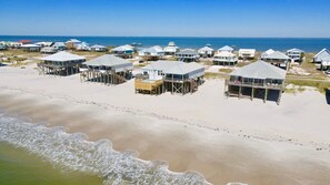 Una propiedad frente a la playa con varias casas elevadas sobre pilotes, unidas por pasarelas y con zonas de estar al aire libre.