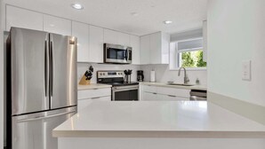 Una cocina moderna con electrodomésticos de acero inoxidable, armarios blancos y una isla central.