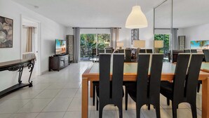 Un comedor con una mesa grande y sillas, un televisor y vistas al exterior.