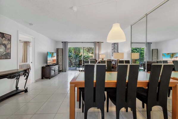 A dining area with a large table and chairs, a television, and a view of the outdoors. - Le Frontenac 204 STR-03583 (Sunny Isles Beach)