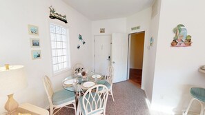 A dining area with a glass table, wicker chairs, and a window with frosted glass.