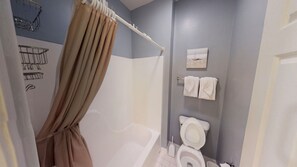 A bathroom with a bathtub, toilet, and shower curtain.