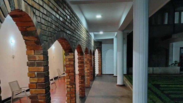 A covered corridor with brick arches and white pillars, leading to a building entrance. - Hotel Lakeside (Anuradhapura)