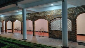 A covered outdoor area with brick arches and columns, seating arrangements, and a patterned wall. - Hotel Lakeside (Anuradhapura)