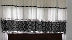 A bed with a white and green bedspread, a dark wooden headboard, and a patterned curtain. - Hotel Lakeside (Anuradhapura)