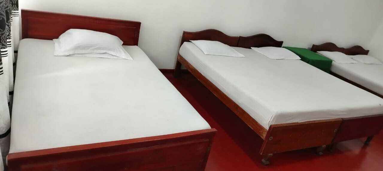 Una habitación con dos camas individuales, cabeceros de madera, ropa de cama blanca y piso rojo.