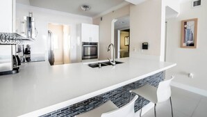 A modern kitchen with a large island, stainless steel appliances, and a black tiled backsplash. - Le Marina Bay 1006 STR-01435 (Sunny Isles Beach)