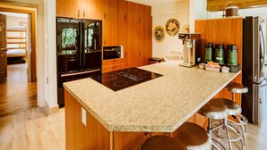 Una cocina moderna con armarios de madera, encimera de granito, electrodomésticos de acero inoxidable y una isla integrada con taburetes de bar.