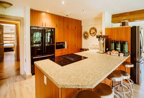 A modern kitchen with wooden cabinets, a granite countertop, stainless steel appliances, and a built-in island with bar stools. - 8-Acre ‘Big House Lodge’ in Cle Elum w/ Hot Tub (Cle Elum)