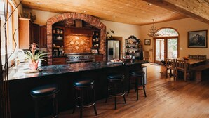 Una cocina con arco de ladrillo, taburetes de madera y una mesa de comedor de madera.