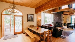 Amplia sala de estar con una mesa de comedor de madera, bancos y una chimenea.
