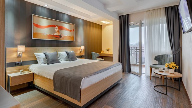 Una habitación de hotel moderna con una cama grande, un escritorio, una silla y un televisor.