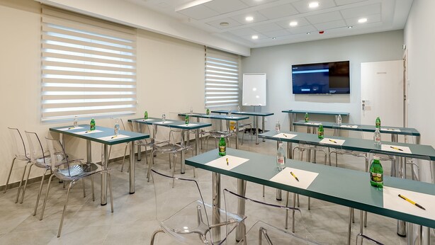 A conference room with tables, chairs, and a projection screen.