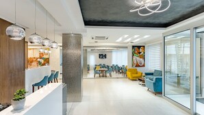 Una moderna zona de recepción con un mostrador blanco, sillas azules y un pilar grande.