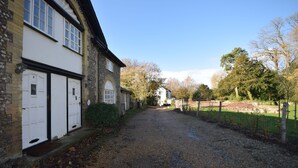 A gravel driveway leading to a white building with black trim and a number '2' on the door. - Flint Cottage , Emsworth  -  a cottage that sleeps 4 guests  in 2 bedrooms (Emsworth)