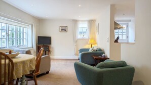 A living room with a dining table, chairs, a television, a sofa, and a lamp. - Flint Cottage , Emsworth  -  a cottage that sleeps 4 guests  in 2 bedrooms (Emsworth)