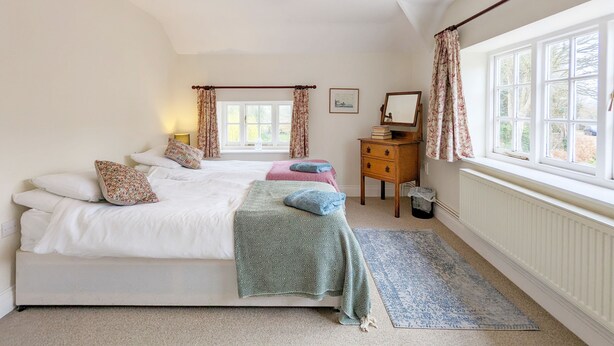 A bedroom with a bed, a dresser, a mirror, and a window with curtains. - Flint Cottage , Emsworth  -  a cottage that sleeps 4 guests  in 2 bedrooms (Emsworth)