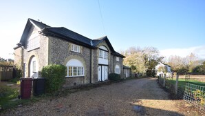 A stone building with a gravel driveway and a fenced area. - Flint Cottage , Emsworth  -  a cottage that sleeps 4 guests  in 2 bedrooms (Emsworth)