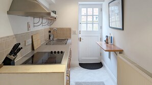 A compact kitchen with a built-in stove, a stainless steel range hood, and a dish rack. - Flint Cottage , Emsworth  -  a cottage that sleeps 4 guests  in 2 bedrooms (Emsworth)