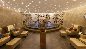 Un espace de détente avec un jacuzzi rond, des canapés de couleur beige et un élément décoratif central.