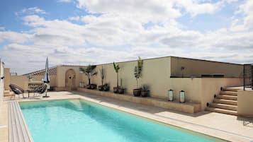 Una piscina al aire libre de temporada, sombrillas, tumbonas