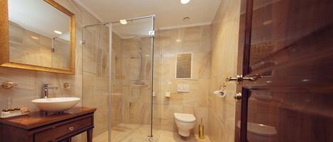 Un baño moderno con ducha de vidrio, tocador con lavamanos y un inodoro.