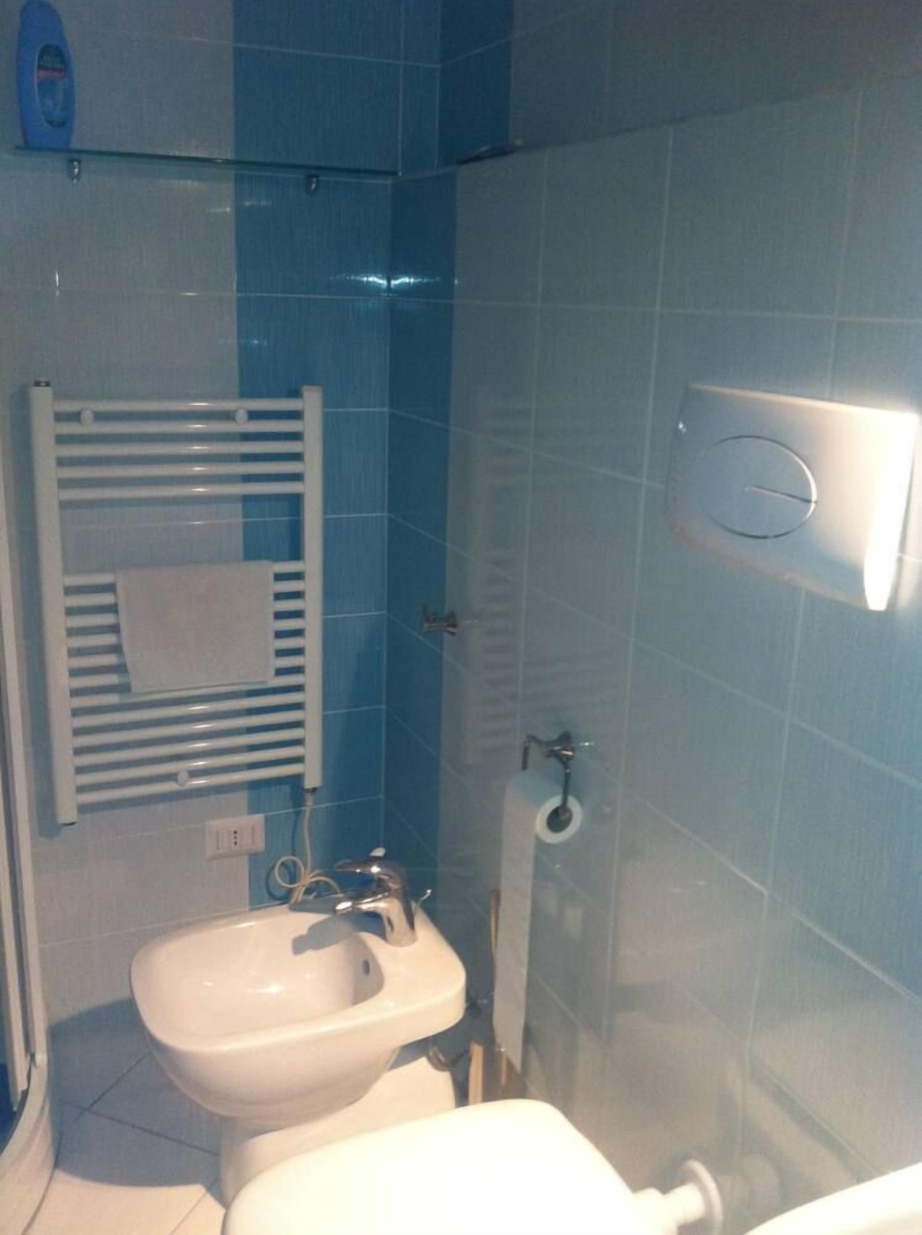 A bathroom with a white sink, a towel rack, and a toilet.
