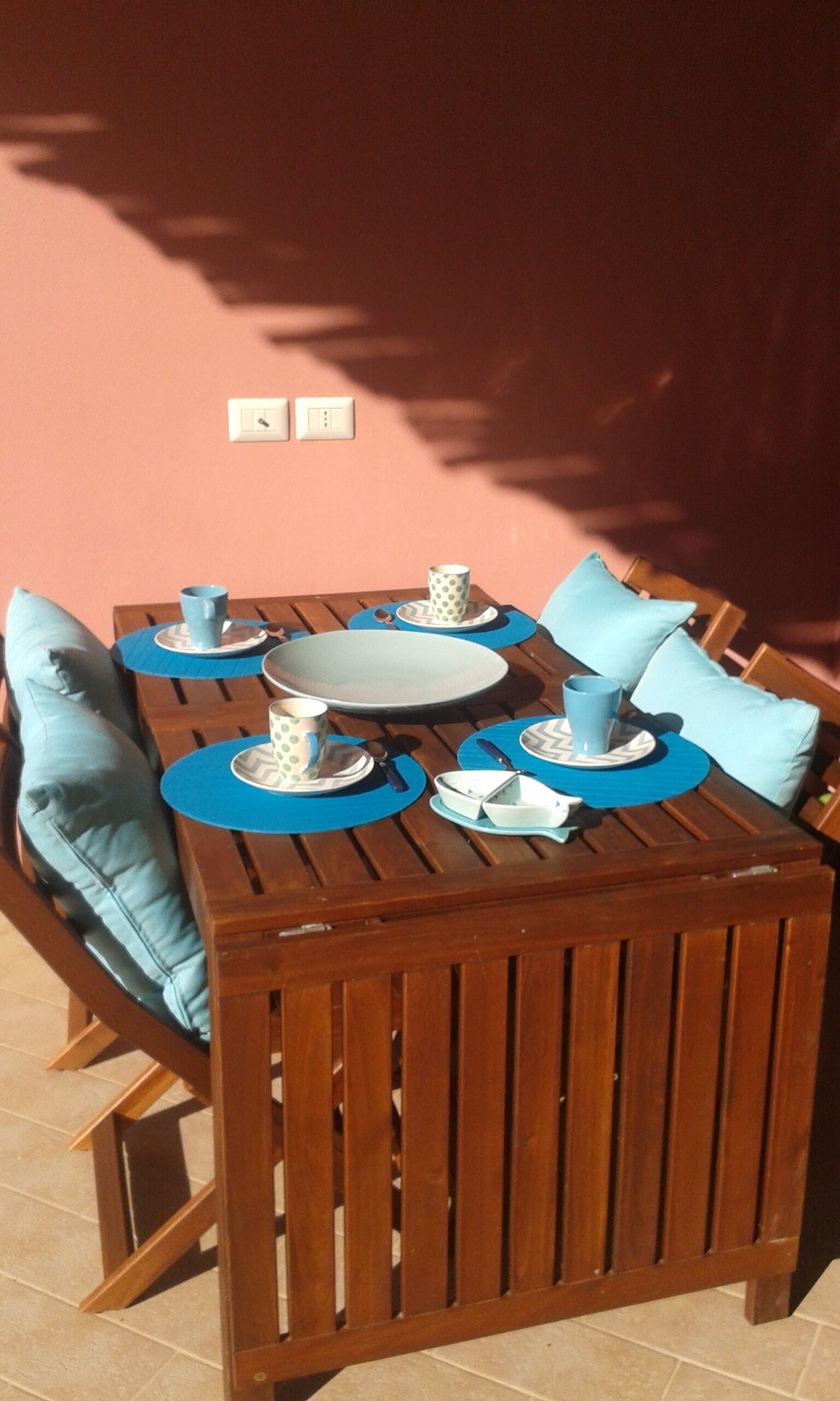 Ein Holztisch mit blauen Tischsets und passenden blauen Kissen.
