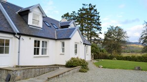 A white house with a grey roof, a small garden, and a view of the countryside. - Shelduck Cottage, shoreline location, pet friendly, sleeps 7 (Glendaruel)