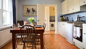 A kitchen with wooden cabinets, a dining table with chairs, a washing machine, and a stove. - Shelduck Cottage, shoreline location, pet friendly, sleeps 7 (Glendaruel)