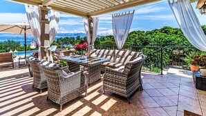 Un espace extérieur aménagé avec des meubles en osier, une table et abrité, offrant une vue sur un paysage montagneux.