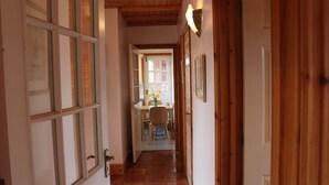 A narrow hallway with wooden doors and windows, leading to a dining area with a table and chairs. - Delightful Detached Cottage close to Exeter, Dartmoor and the coast. (Longdown)