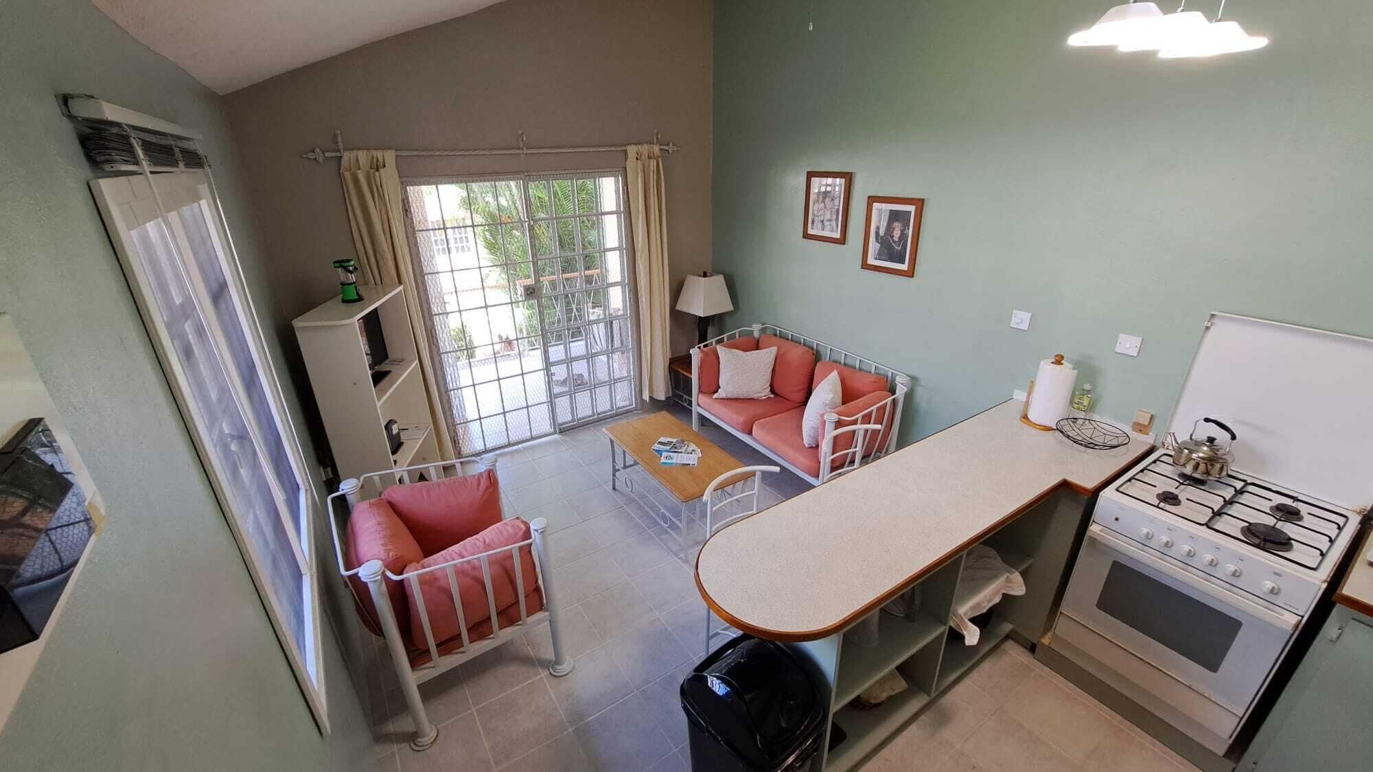 A compact kitchen with a stove, a dining table, and a sofa.