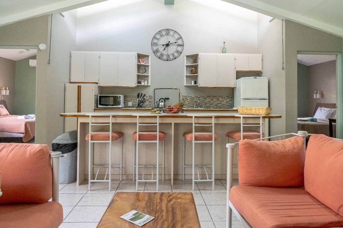 Un espace de vie compact comprenant un coin cuisine, un coin repas avec des tabourets et un canapé.