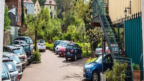 Ein Parkplatz mit Autos, ein Gebäude mit einer Treppe und eine Burg im Hintergrund.
