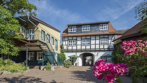 Ein Innenhof mit einem traditionellen Fachwerkhäuschen, einem überdachten Eingang und einem gepflasterten Weg.