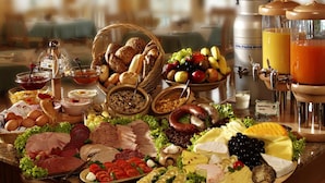 Ein reichhaltiges Buffet mit verschiedenen Speisen, darunter Fleisch, Käse, Obst und Getränke.