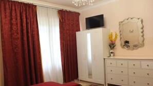 Une chambre à coucher avec un lit, une armoire, une télévision et un miroir.